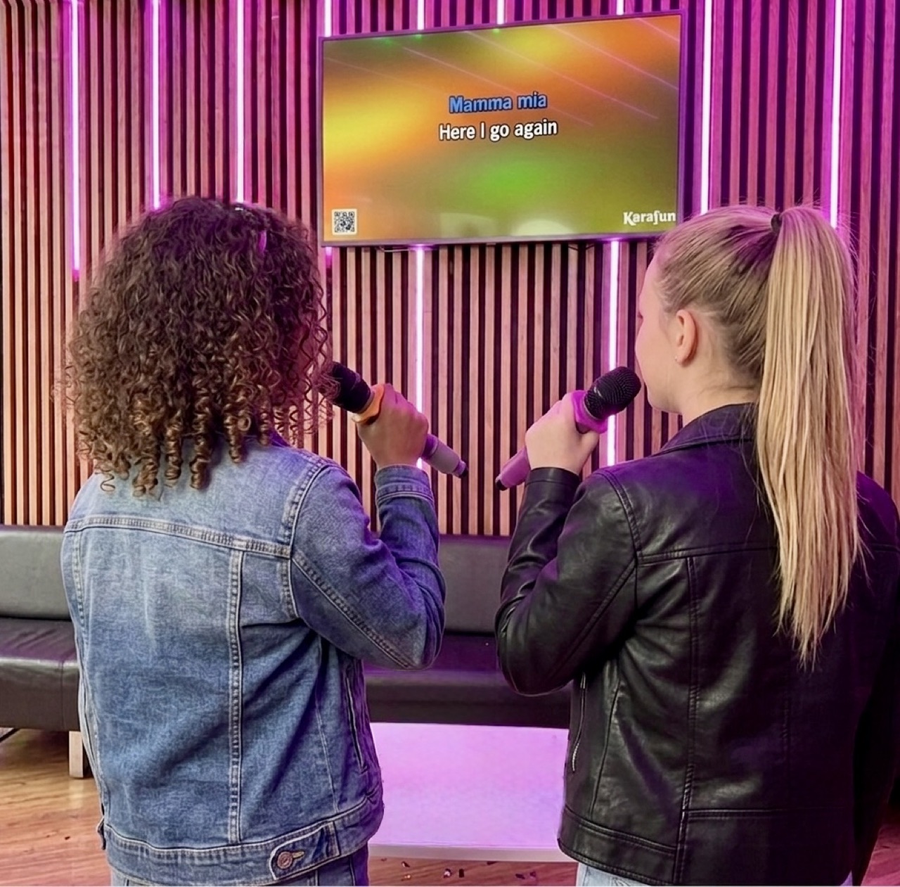 Un duo d’enfants chante face à l’écran de karaoké.